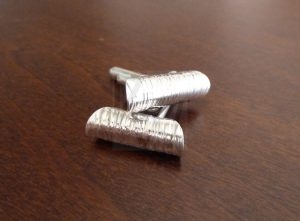 Pareja de gemelos artesanales de Plata de Ley 925 con un diseño escultórico inspirado en el océano; la pieza decorativa consiste en un disco martillado y plegado sobre sí mismo hasta formar una estructura tubular que recrea la curvatura de las olas del mar, capturando reflejos de luz únicos gracias a su superficie texturizada.