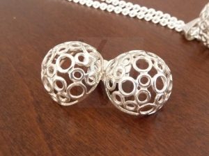 Pendientes artesanales de plata con diseño calado en forma de semiesfera; la pieza está compuesta por una intrincada estructura de numerosos aros pequeños de Plata de Ley 925 que se juntan para crear un volumen ligero y transparente.