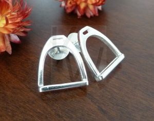 Pareja de pendientes artesanales de plata con una silueta estilizada en forma de estribo; el diseño presenta líneas limpias y un acabado pulido que resalta la forma geométrica y clásica de esta pieza realizada en Plata de Ley 925.