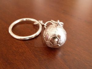 Llavero artesanal realizado en Plata de Ley 925 compuesto por un aro principal del que pende, mediante una cadena, una pelota de fútbol de plata masiva; el diseño destaca por su volumen y el detallado relieve de sus paneles, ofreciendo una pieza robusta y de gran calidad que rinde homenaje a la pasión por el fútbol.