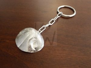 Llavero artesanal realizado en Plata de Ley 925 compuesto por un aro principal y una cadena que sostiene una reproducción detallada de la nariz o trufa de un perro; el diseño destaca por capturar cada relieve y textura característica de forma realista, convirtiéndose en un símbolo de fidelidad y conexión con el mundo canino.