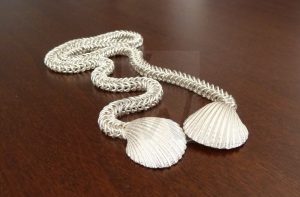 Espectacular collar artesanal de Plata de Ley 925 compuesto por una cadena elaborada meticulosamente a mano; en cada extremo presenta una concha marina de diseño realista que cumple una doble función: actuar como motivo ornamental y ocultar de forma ingeniosa el cierre de la pieza, manteniendo la armonía estética en todo su recorrido.