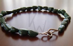 Collar artesanal formado por una hilera de piedras de malaquita pulida de intenso color verde; la pieza cuenta con un cierre único de Plata de Ley 925 compuesto por dos aros irregulares que se entrelazan mediante una sutil apertura, uniendo funcionalidad y diseño orgánico.