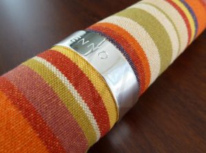 Aro de servilleta artesanal realizado en Plata de Ley 925 con un diseño de banda clásica y terminación pulida de alto brillo; la superficie presenta un acabado espejo impecable que resalta el estampado de un nombre personalizado. Un accesorio de mesa distinguido que combina la elegancia del metal noble con la identidad propia, ideal para eventos especiales o como regalo de hogar exclusivo.