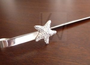 Marcapáginas artesanal de plata diseñado para quedar integrado entre las páginas, rematado en su extremo por una estrella de mar de Plata de Ley 925; el motivo queda fijo y sobresale delicadamente por fuera del libro, aportando un toque marino elegante y exclusivo a su punto de lectura.