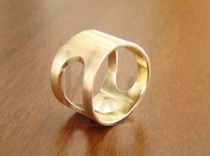 Anillo artesanal de banda ancha realizado en oro de 18k, caracterizado por un diseño calado del que se han recortado dos formas ovaladas paralelas, creando un juego de espacios vacíos que aporta ligereza y modernidad a la pieza.