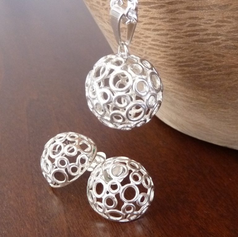 Conjunto de joyería artesanal compuesto por colgante y pendientes en forma de bola, diseñados con círculos de plata unidos creando un efecto de burbujas ligeras y elegantes.