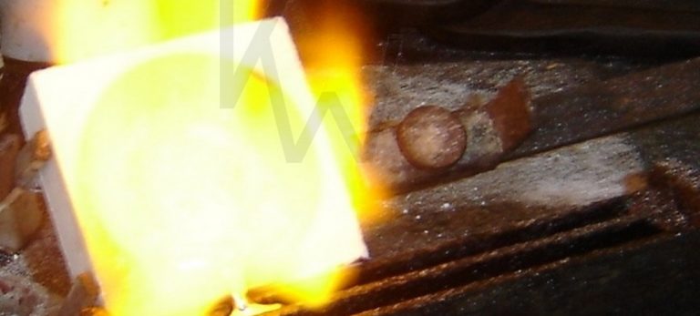 Primer plano de un crisol con plata fundida bajo la llama de un soplete, en el momento previo a ser vertida en la hilera para crear una pieza de joyería artesanal única.